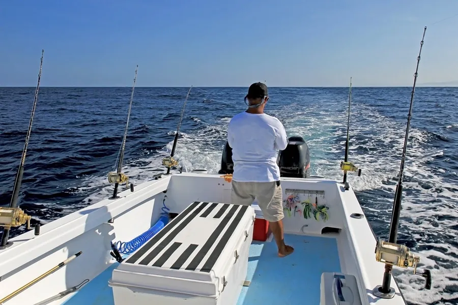 Sportfiskare drillar fisk under trollingfiske från båt